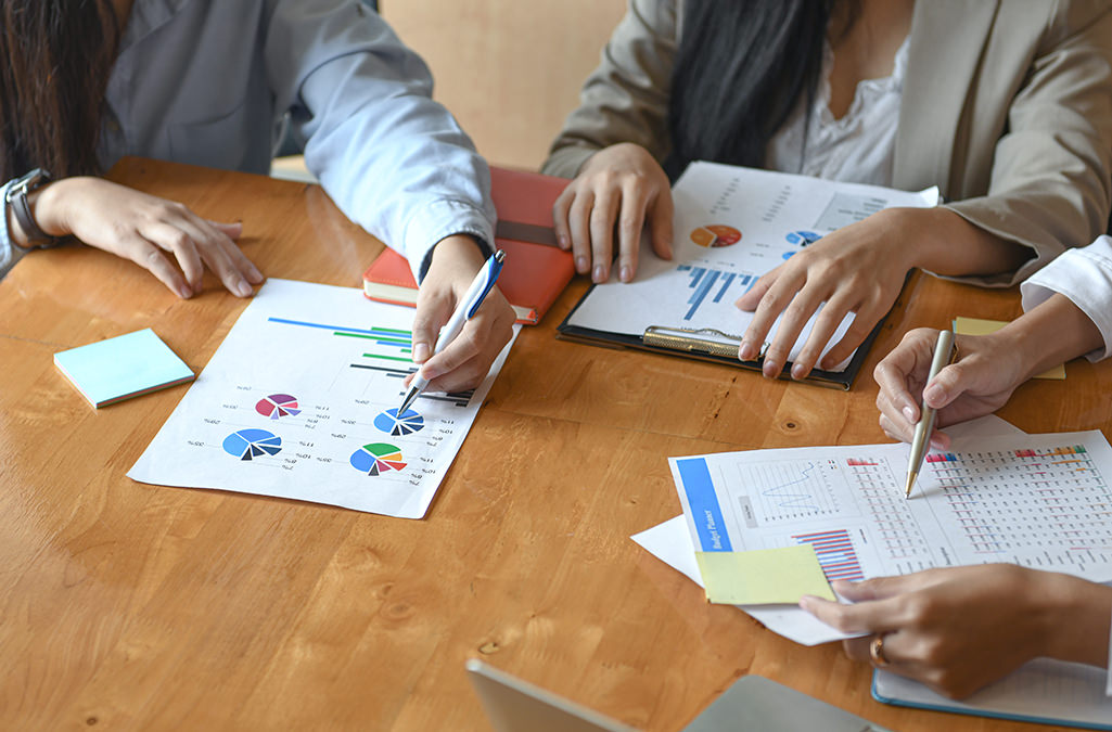 Female office staff team summarizes the budget for the annual executive presentation.They analyzed the data graph on the desk